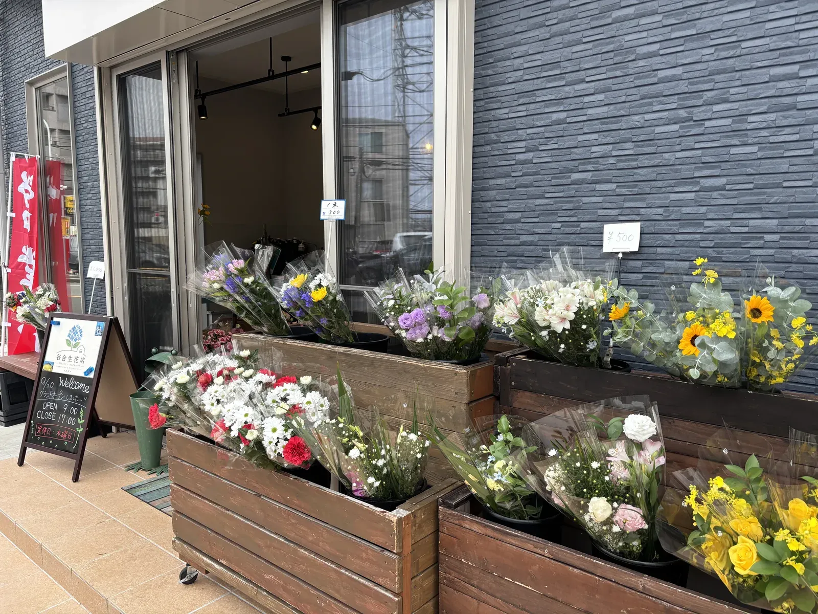 谷合生花店の店頭。木箱に季節の花束が並ぶ